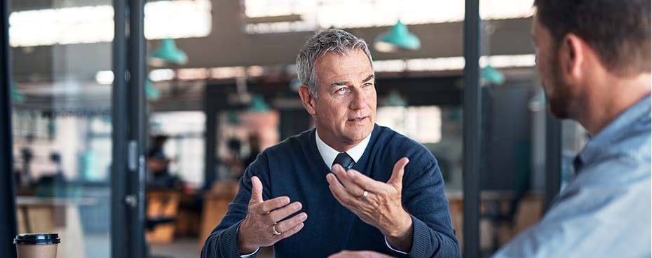 Man met collega in gesprek op kantoor Man met collega in gesprek op kantoor